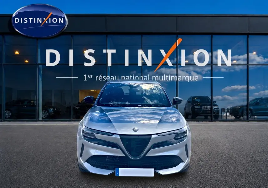 Vue frontale d'une Alfa Romeo Junior 1.2 hybride grise, avec calandre triangulaire caractéristique et phares LED.