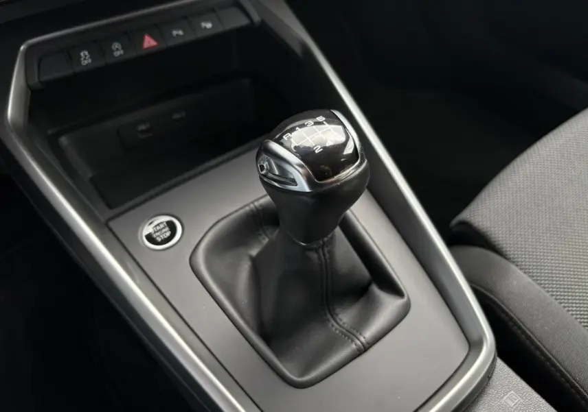 Gros plan sur le levier de vitesse manuelle noir et argenté de l'Audi A3 Berline 35 TFSI gris, avec bouton start/stop visible.