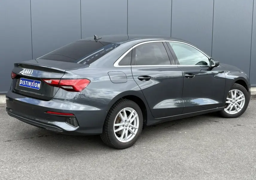 Audi A3 Berline gris métallisé vue 3/4 arrière droit avec vitres surteintées et jantes argentées.