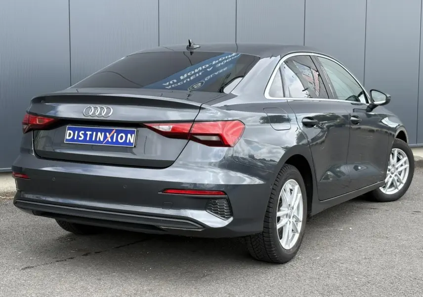 Audi A3 Berline gris métallisé vue 3/4 arrière droit avec vitres surteintées et jantes argentées.
