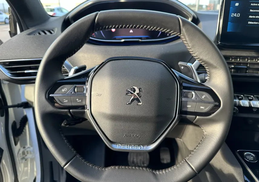Volant cuir noir de Peugeot 3008 2024 avec commandes intégrées, tableau de bord numérique et écran tactile visible à droite.