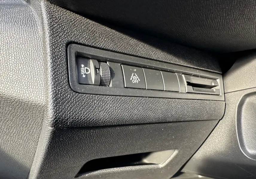Gros plan sur les commandes de réglage des phares et désactivation de l'assistance au maintien de voie du Peugeot 3008 2024.