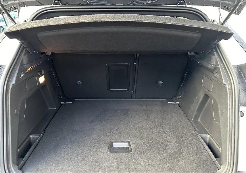 Coffre ouvert vu de l'arrière d'un Peugeot 3008 blanc nacré, espace de chargement propre et spacieux.