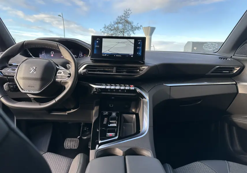 Intérieur du Peugeot 3008 2024 en vue avant, tableau de bord noir avec écran tactile central et volant compact.