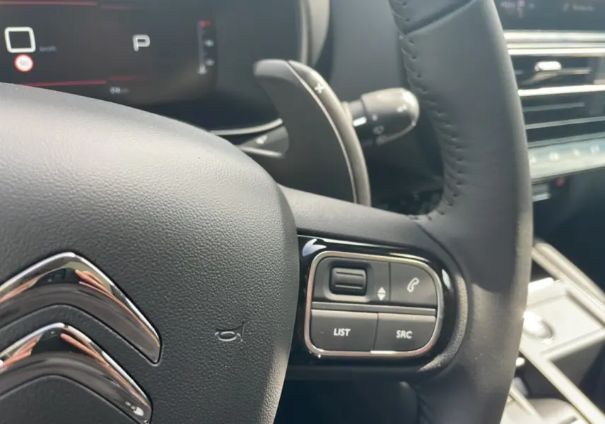 Détail du volant noir du Citroën C5 Aircross Hybrid 2025 avec commandes intégrées et palettes au volant.