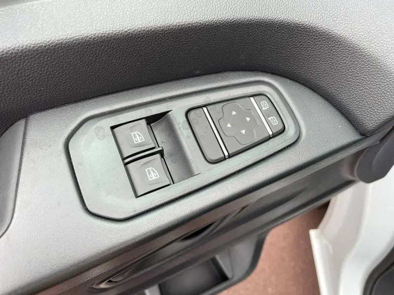 Détail des commandes de lève-vitres et réglage des rétroviseurs côté conducteur du Renault Trafic Fourgon blanc Glacier 2024.
