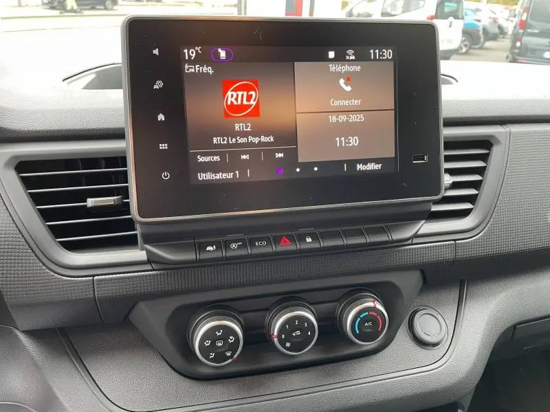 Tableau de bord du Renault Trafic Fourgon 2024 avec écran tactile et commandes climatisation en vue frontale rapprochée.