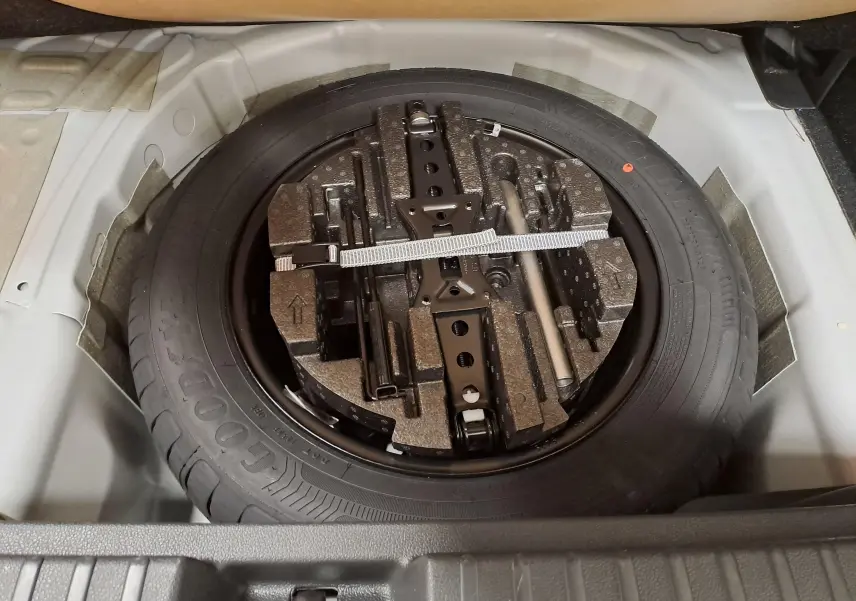 Vue plongeante sur la roue de secours et ses outils dans le coffre du Skoda Kamiq blanc Lune 2025.