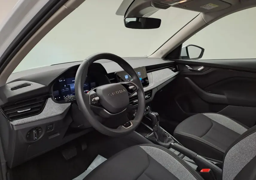 Intérieur de la Skoda Kamiq 2025 vu côté conducteur, tableau de bord moderne avec écran tactile et volant multifonction.