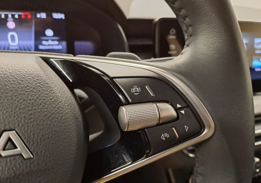 Gros plan sur les commandes au volant en cuir noir du Skoda Kamiq 2025, mettant en valeur la molette métallique et les boutons intégrés.