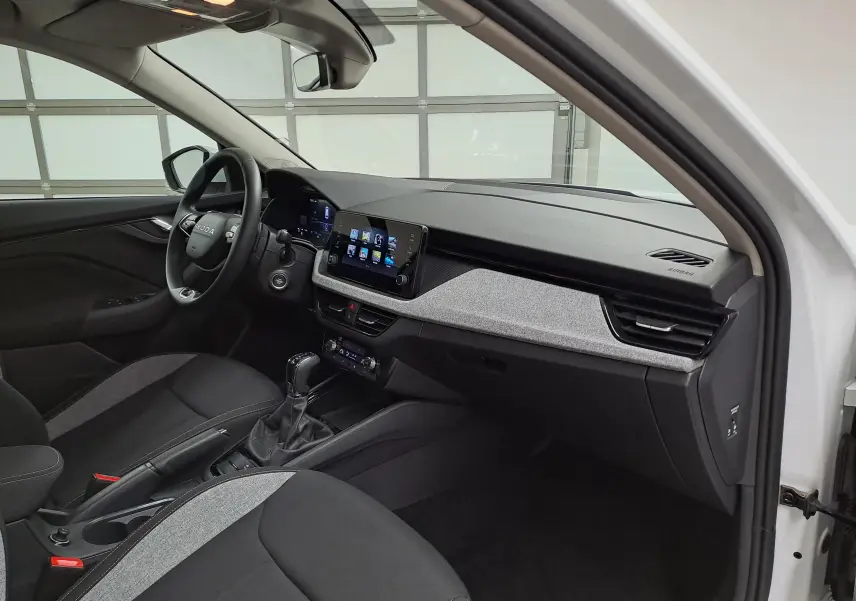 Vue intérieure côté conducteur du Skoda Kamiq blanc Lune 2025, avec tableau de bord moderne et écran tactile central.