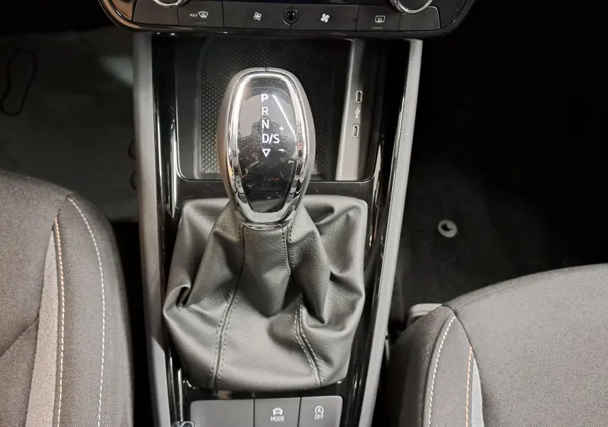 Vue rapprochée du levier de vitesses automatique noir et chrome du Skoda Kamiq 2025, entouré de sièges tissu gris.