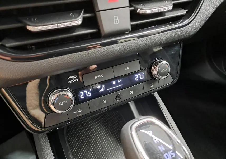 Gros plan sur la console centrale noire du Skoda Kamiq 2025, avec commandes climatisation digitale et levier de boîte automatique.