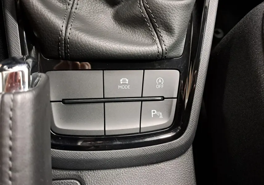 Gros plan sur les commandes de la console centrale du Skoda Kamiq 2025, avec bouton mode conduite et radar de stationnement.