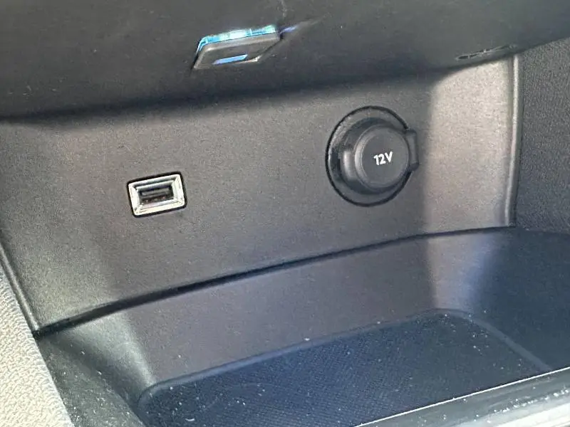 Gros plan sur la prise 12V et port USB dans le rangement intérieur du Peugeot 3008 Hybride Rechargeable noir Perla Nera.