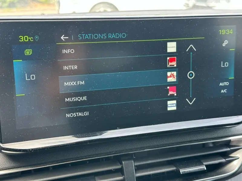 Écran tactile central du Peugeot 3008 Hybride Rechargeable 2024 affichant les stations radio, intérieur noir.
