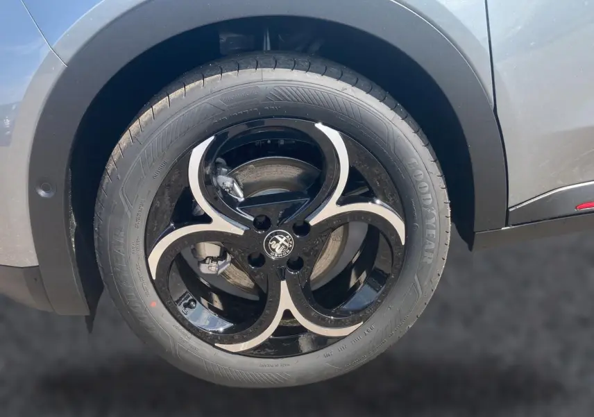 Gros plan sur la jante alliage noire et argentée côté droit de l'Alfa Romeo Junior gris t/noir, mettant en valeur le logo central.