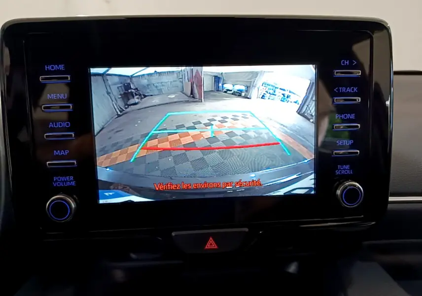 Écran tactile central de la Toyota Yaris hybride 2021 montrant la caméra de recul avec lignes de guidage colorées.