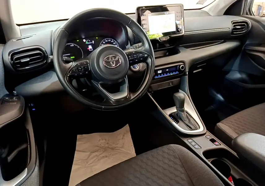 Intérieur noir de la Toyota Yaris Hybride 2021 vu côté conducteur, avec volant multifonctions et écran tactile central.