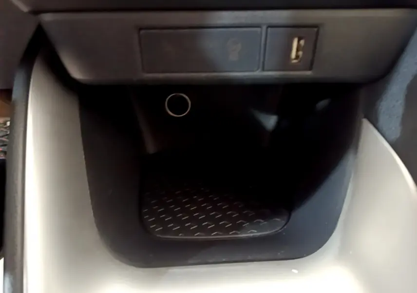 Gros plan sur la prise USB et l’allume-cigare dans le rangement central noir de la Toyota Yaris hybride gris clair 2021.