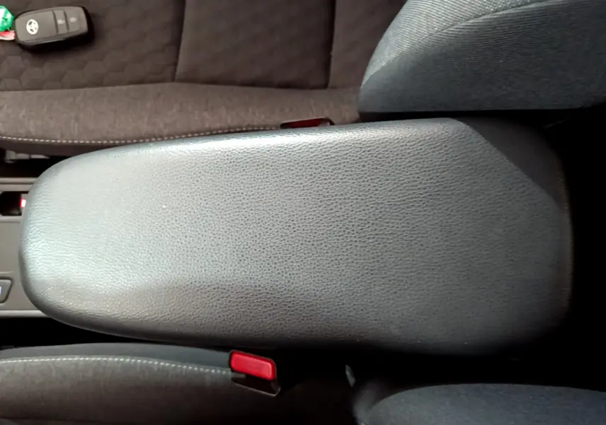 Vue rapprochée de l'accoudoir central gris foncé de la Toyota Yaris hybride 2021 avec clé posée sur le siège adjacent.