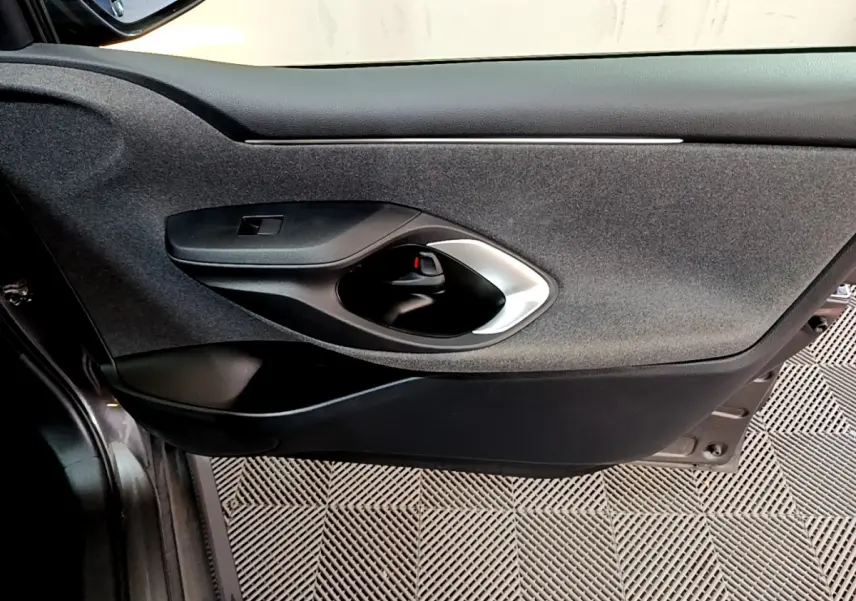 Gros plan sur la porte côté gauche intérieure noire de la Toyota Yaris hybride 2021, avec poignée argentée et tissu gris.