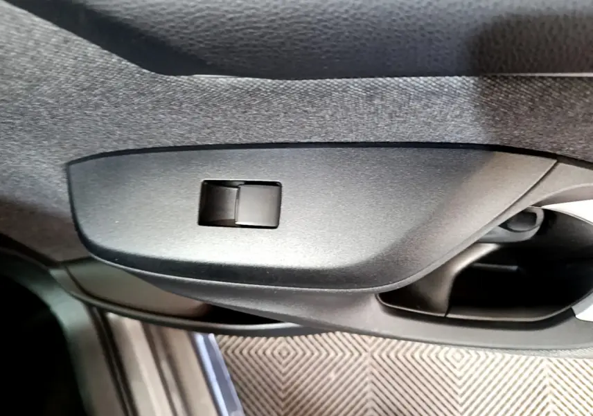 Détail de la poignée intérieure côté gauche de la Toyota Yaris hybride gris clair, avec bouton de verrouillage intégré.