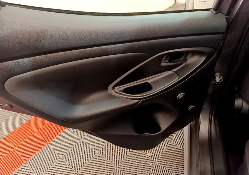 Porte intérieure côté gauche de Toyota Yaris hybride 2021, en plastique noir avec poignée intégrée et rangement.