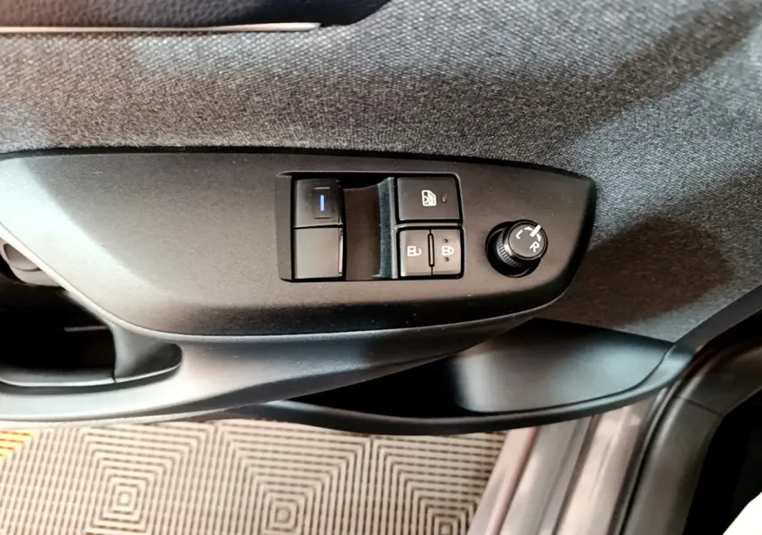 Vue rapprochée des commandes de réglage des rétroviseurs et des vitres côté conducteur d'une Toyota Yaris hybride gris clair 2021.