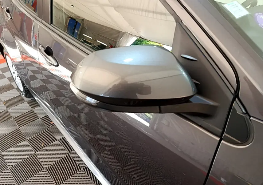 Rétroviseur côté droit gris clair de la Toyota Yaris Hybride 116h 2021 avec poignée de porte visible en reflet.