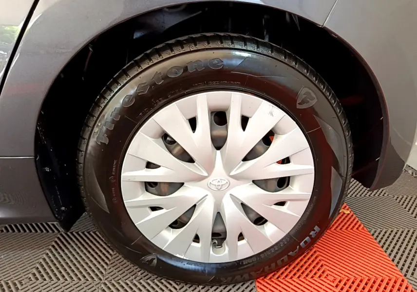 Gros plan sur la roue avant gauche grise de la Toyota Yaris hybride avec enjoliveur argenté et pneu Firestone.