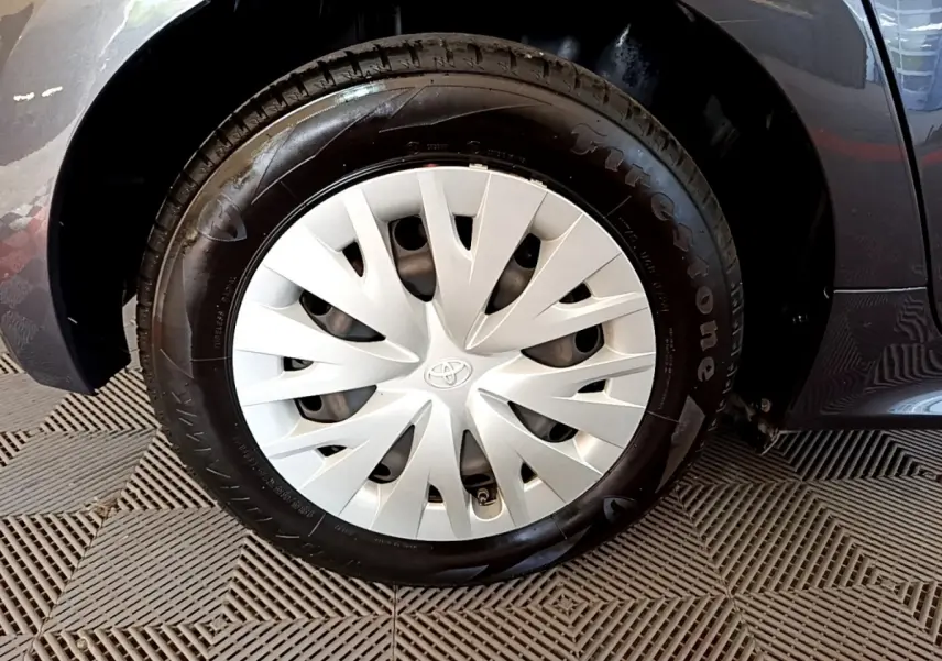 Gros plan sur la roue avant droite grise d'une Toyota Yaris hybride 2021 avec enjoliveur Toyota et pneu Firestone.