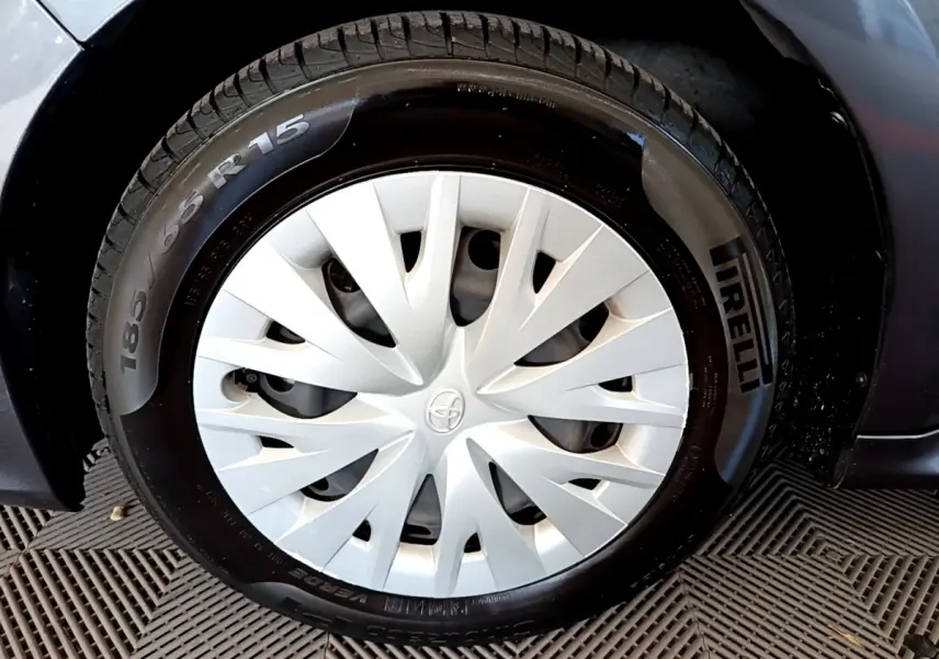 Gros plan sur la roue avant gauche grise d'une Toyota Yaris hybride avec enjoliveur blanc et pneu Pirelli.