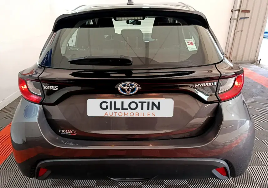 Vue arrière d'une Toyota Yaris hybride gris clair avec badges Yaris, Hybrid et France visibles sur le hayon.