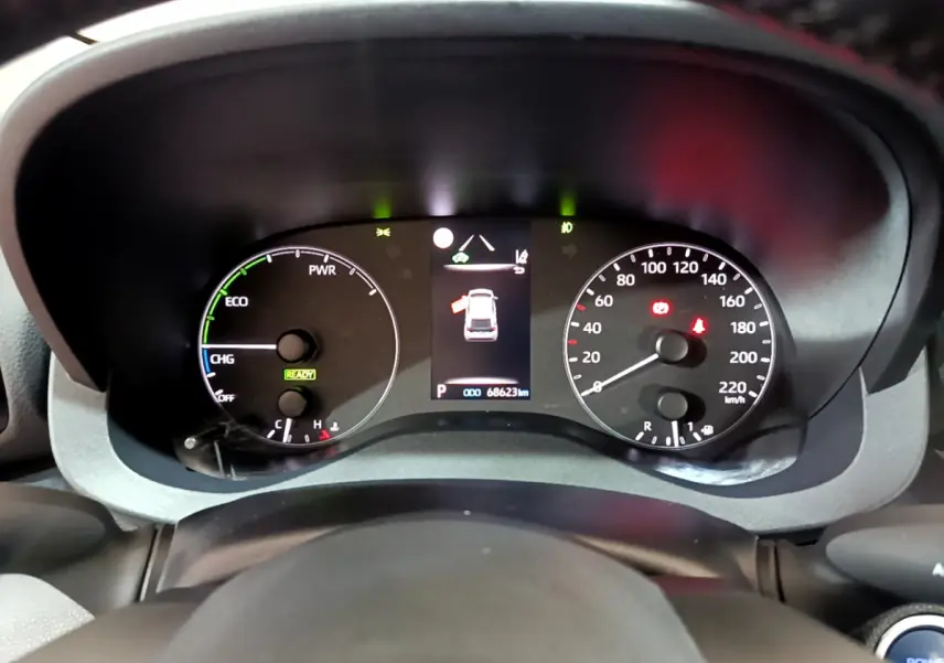 Tableau de bord de Toyota Yaris hybride 2021 vu de face, affichage numérique et compteurs analogiques blancs.