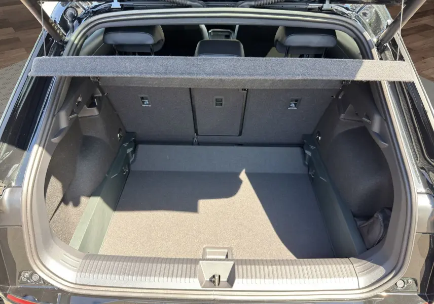 Vue arrière du coffre ouvert du Volkswagen T-Roc noir ébène 2026, montrant l'espace de chargement et la banquette arrière.