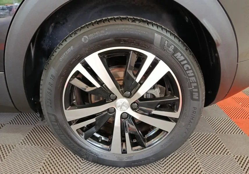 Gros plan sur la roue avant droite du Peugeot 3008 noir, avec jante alliage bicolore et pneu Michelin.