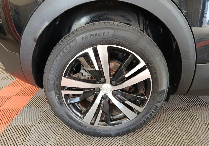 Gros plan sur la roue avant gauche noire du Peugeot 3008 PureTech 130 GT avec jante alliage bicolore.