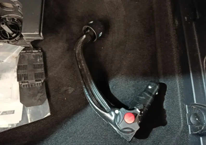 Gros plan sur l'attelage de remorque noir posé sur le tapis intérieur du coffre d'un Peugeot 3008 noir.