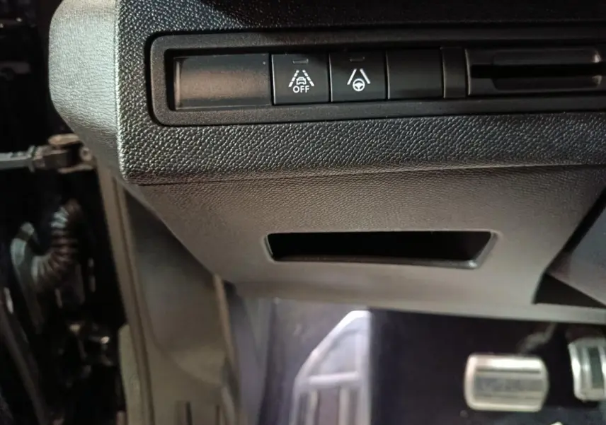 Vue rapprochée des commandes d’aide à la conduite sous le tableau de bord du Peugeot 3008 noir, version GT 2022.