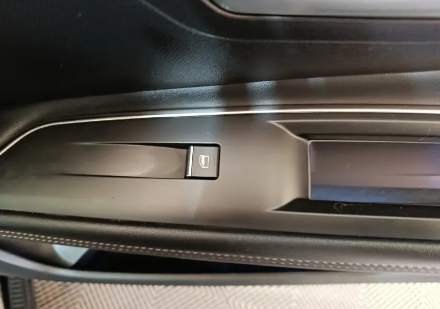 Détail de la commande de lève-vitre sur la porte côté gauche intérieure d’un Peugeot 3008 noir 2022.