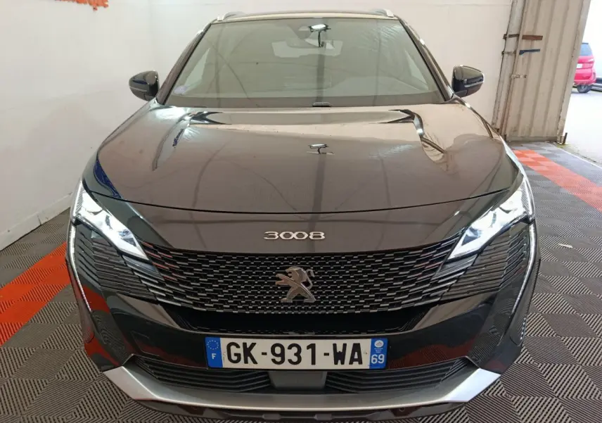 Vue avant d'un Peugeot 3008 noir 2022 avec calandre distinctive et phares LED allumés en intérieur.