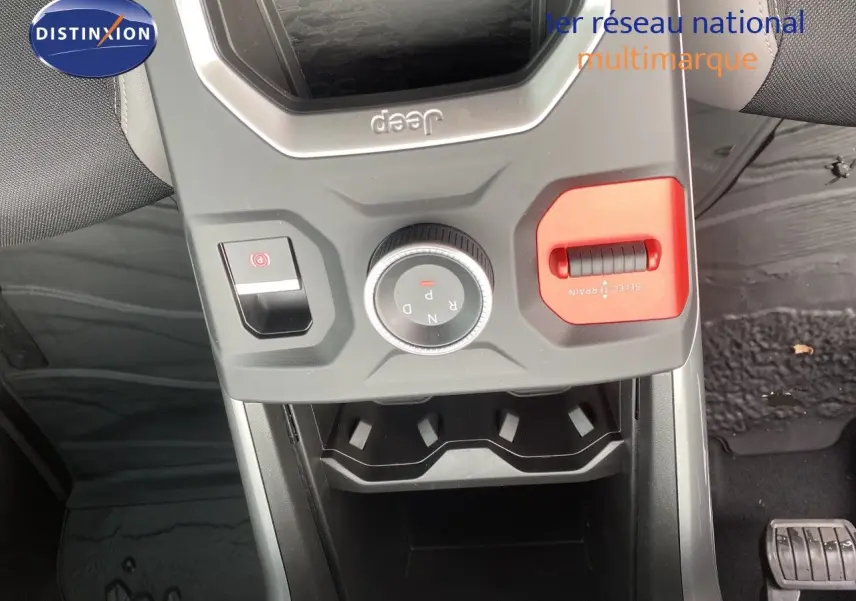 Vue plongeante sur la console centrale du Jeep Compass noir Vulcano, mettant en valeur la molette de boîte auto et le sélecteur terrain rouge.