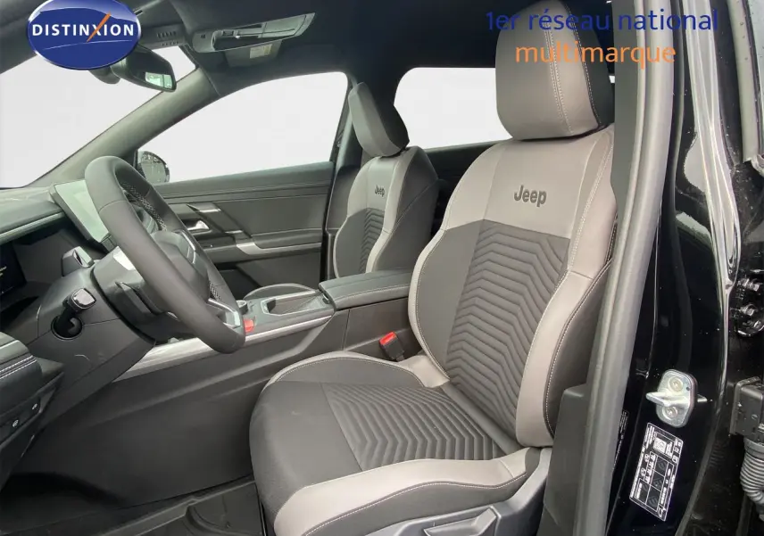 Vue intérieure côté conducteur du Jeep Compass noir Vulcano, sièges bi-ton gris avec logo Jeep brodé sur appuie-tête.