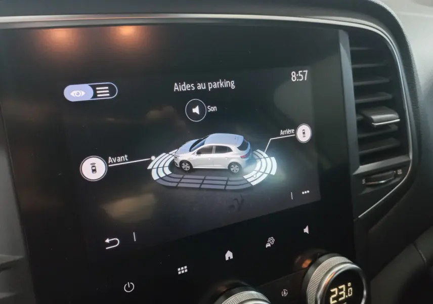 Écran tactile intérieur affichant l'aide au parking d'une Renault Mégane Business blanche, avec commandes climatisation visibles.