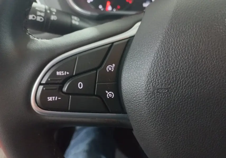 Gros plan sur les commandes du régulateur de vitesse au volant noir de la Renault Mégane Business 2022.