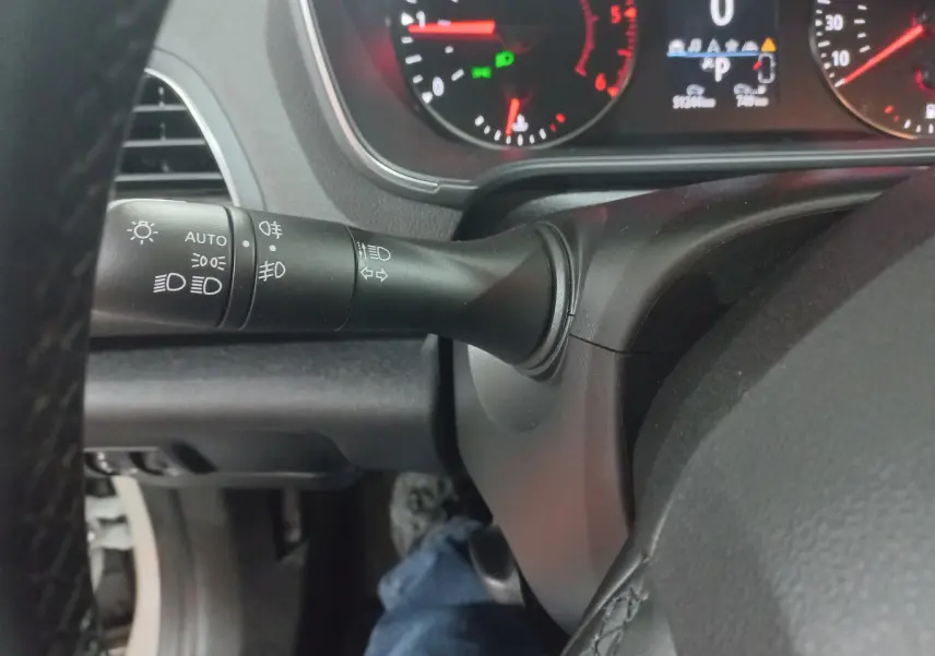 Gros plan sur la manette des feux et clignotants à gauche du volant dans le tableau de bord de la Renault Mégane Business blanche 2022.