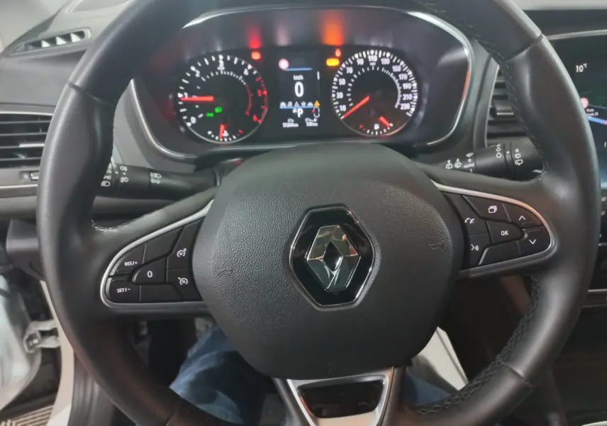 Vue rapprochée du volant noir de la Renault Mégane Business avec tableau de bord numérique allumé.