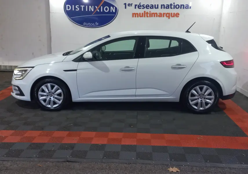 Profil côté gauche d'une Renault Mégane Business Blue dCi 115 EDC blanche, avec feux arrière allumés en intérieur showroom.