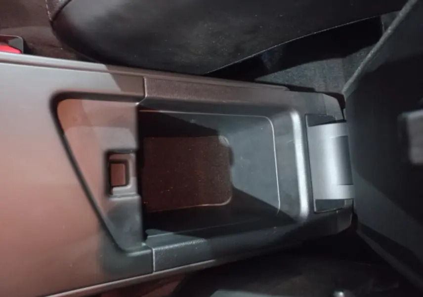 Vue rapprochée du rangement central noir ouvert entre les sièges avant d'une Renault Mégane Business blanche 2022.